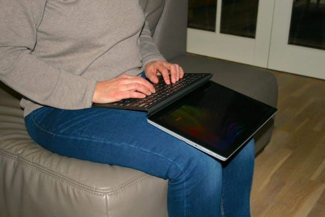 Een vrouw zit op een bank met een laptop.