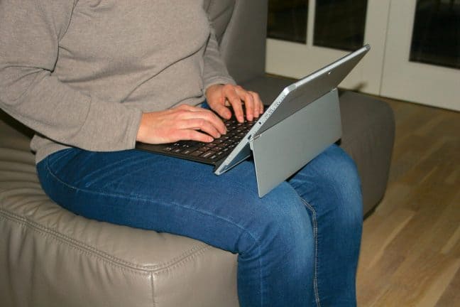 Een vrouw zit op een bank met een laptop.