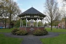 Midden in een park staat een bakstenen tuinhuisje.