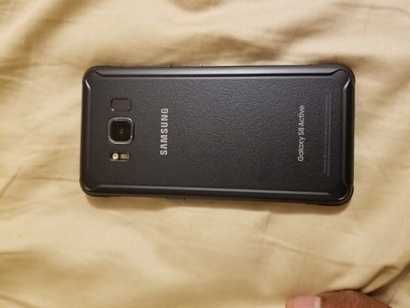 Een zwarte Samsung Galaxy S8 Active op een bed.