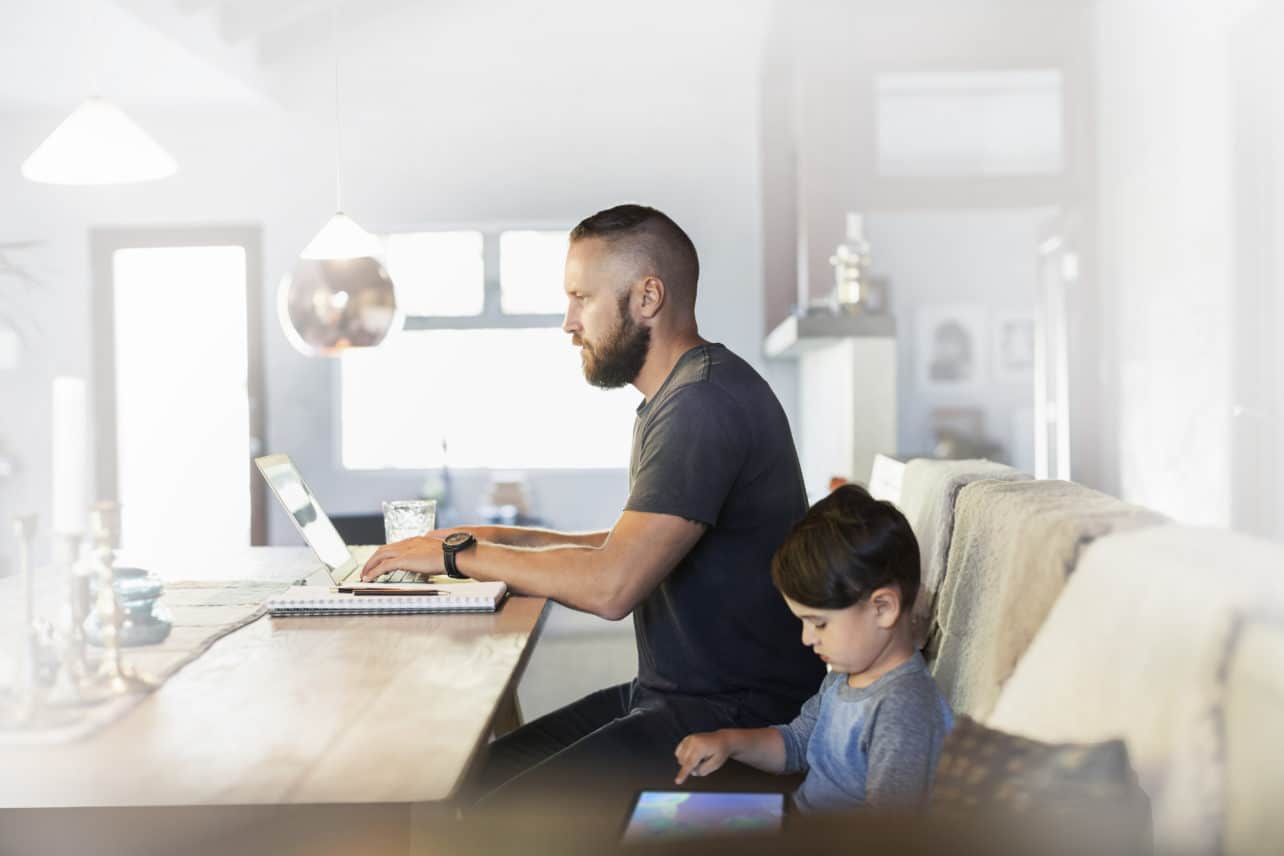 Side view of father and son using technologies at dining table