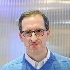 Een man met een bril en een blauwe trui.