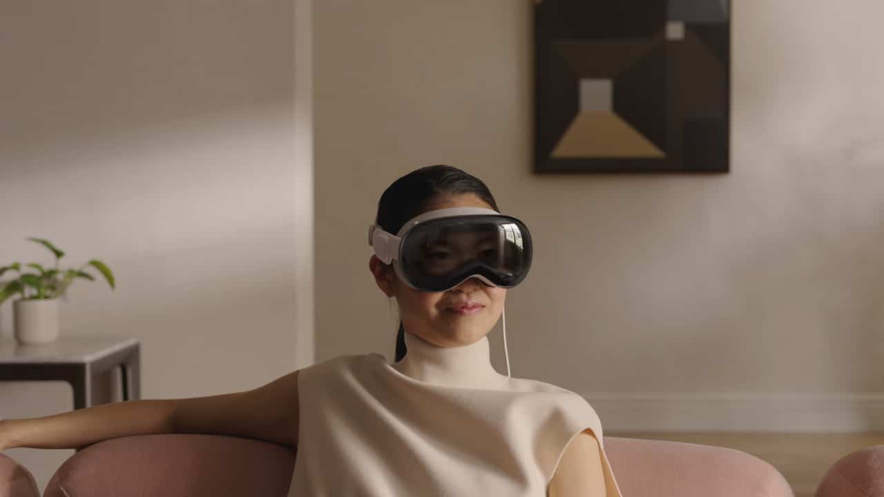 visionpro4 Een vrouw met een VR-headset zittend op een bank.