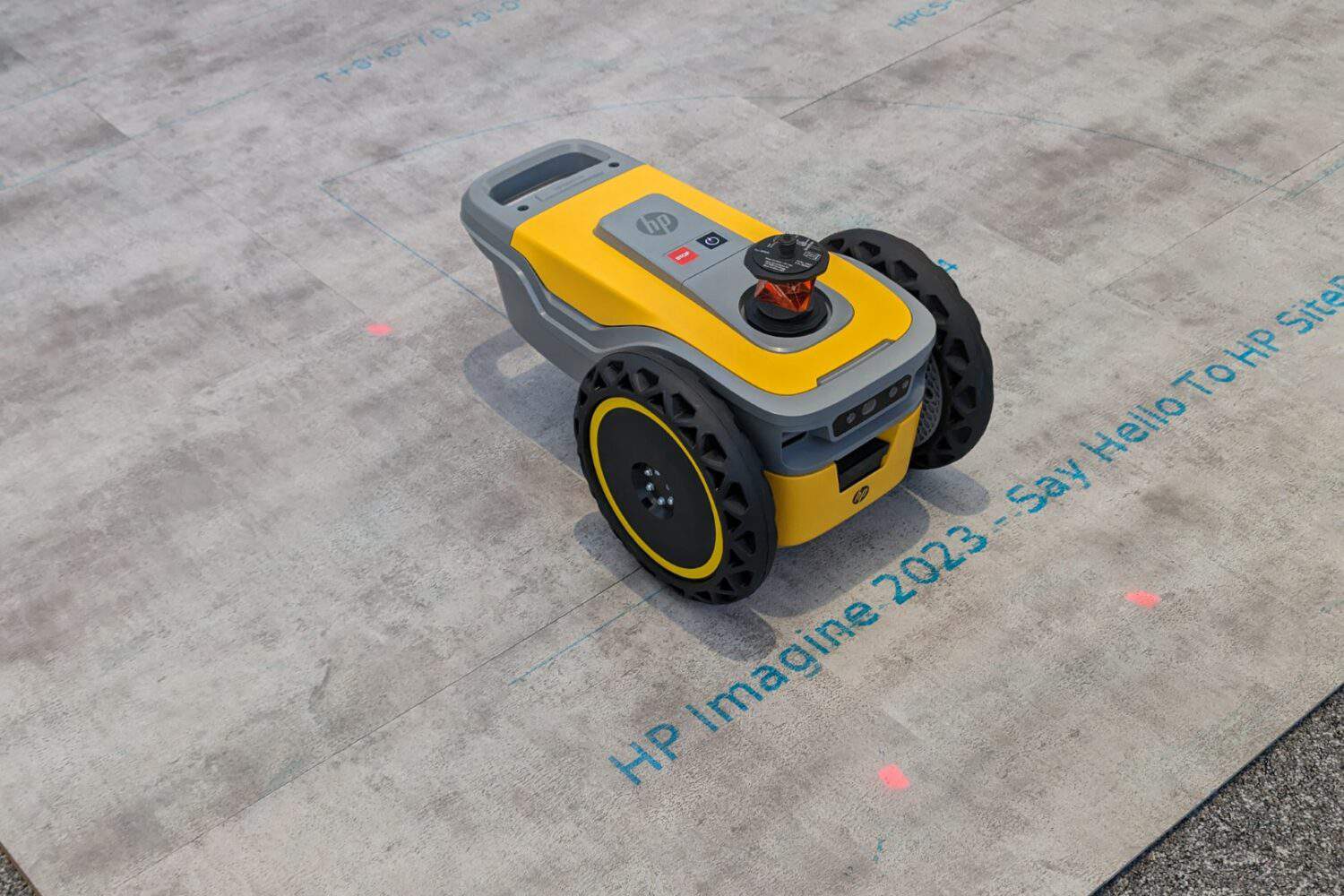 Een gele robot op een betonnen vloer.