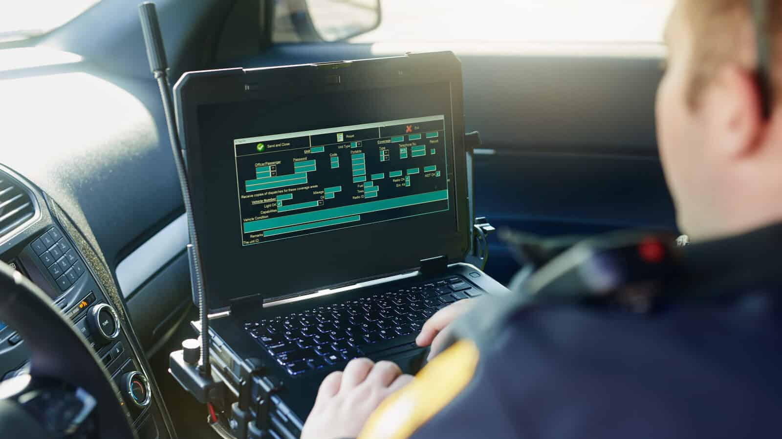 Een politieagent gebruikt een laptop in zijn auto.