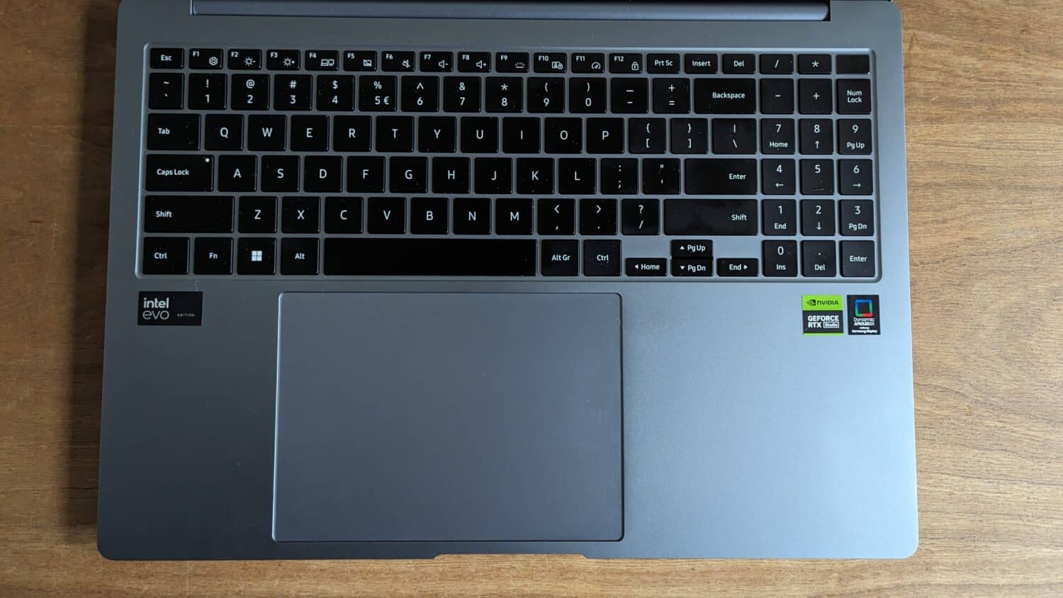 Close-up van een Galaxy Book4 Ultra-laptoptoetsenbord en touchpad op een houten oppervlak, met Intel Evo- en Nvidia-stickers.