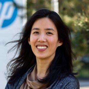 Een persoon lacht voor het HP-logo op een wegwijzer buiten.