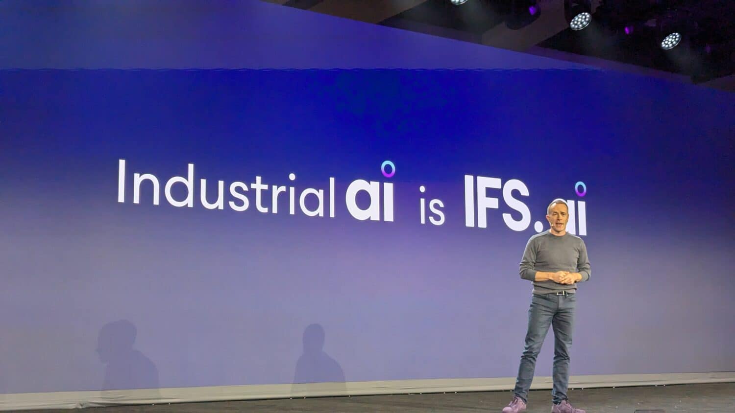 PXL_20241015_123507362.MP Een persoon staat op een podium met een groot scherm waarop de tekst 'Industriële ai is IFS.ai' staat.