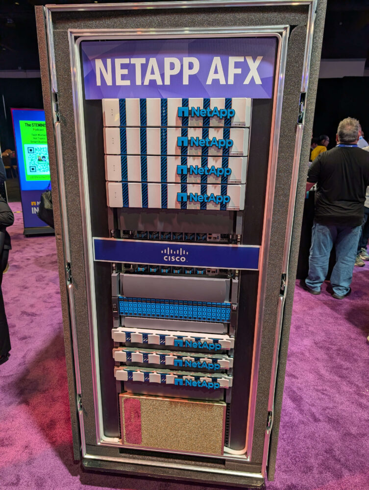 NetApp AFX_2 Een serverrack met meerdere hardwarecomponenten van NetApp en Cisco, waaronder NetApp AFX, wordt getoond op een paars tapijt tijdens een technologie-evenement.
