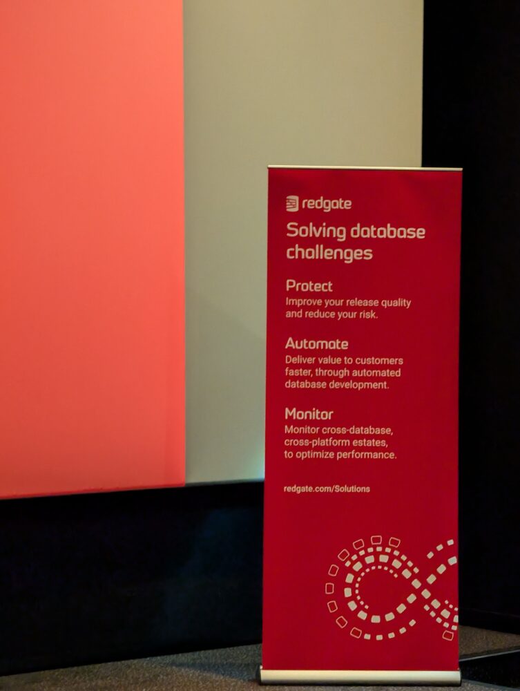 PXL_20251003_080054496 Een rode banner staat naast een scherm met daarop de Redgate branding en bullet points over het oplossen van database uitdagingen: Beschermen, Automatiseren en Bewaken.