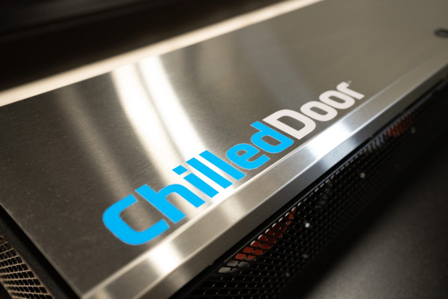 Close-up van een metalen paneel met de tekst "ChilledDoor" in blauwe en witte letters, met daaronder een gaasgedeelte.